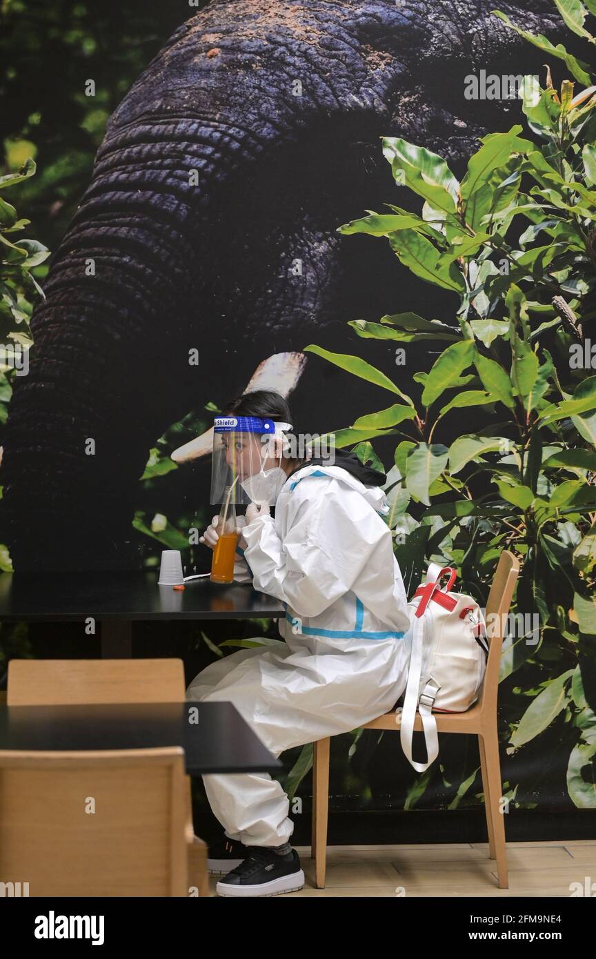 COSTA DE MARFIL, Abiyán, aeropuerto, locura de corona, mujer china viajero con protección corporal completa durante la pandemia de Corona, beber jugo en restaurante del aeropuerto / ELFENBEINKÜSTE, Abiyán, Flughafen, Chinesische Reisende en Schutzkleidung während der Corona Pandemie Foto de stock