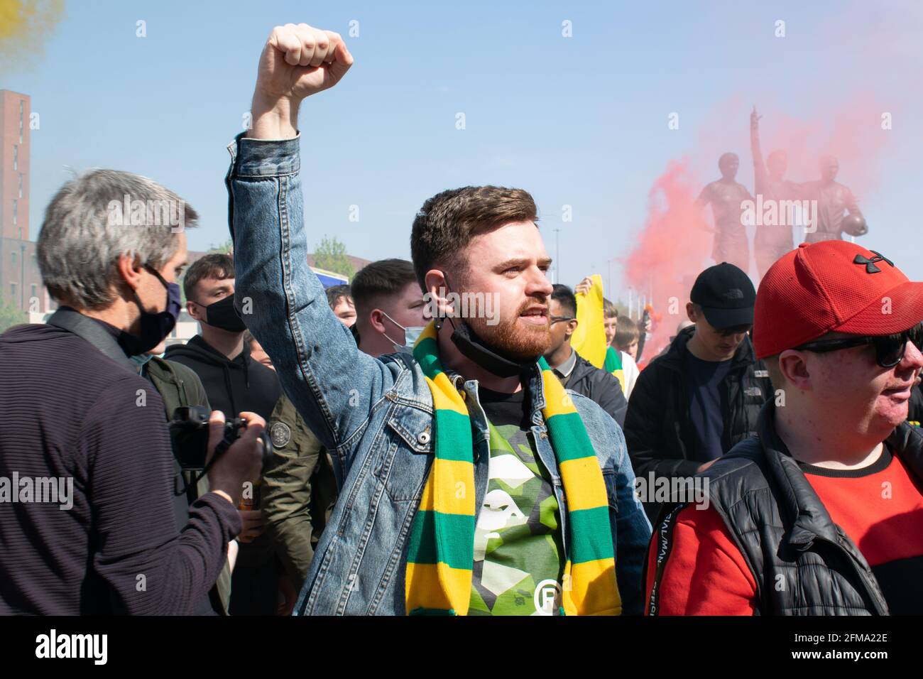 Protesta contra Glazer en el campo de fútbol Old Trafford. Apoyo sujetando el puño hacia arriba y usando bufanda verde y dorada Foto de stock