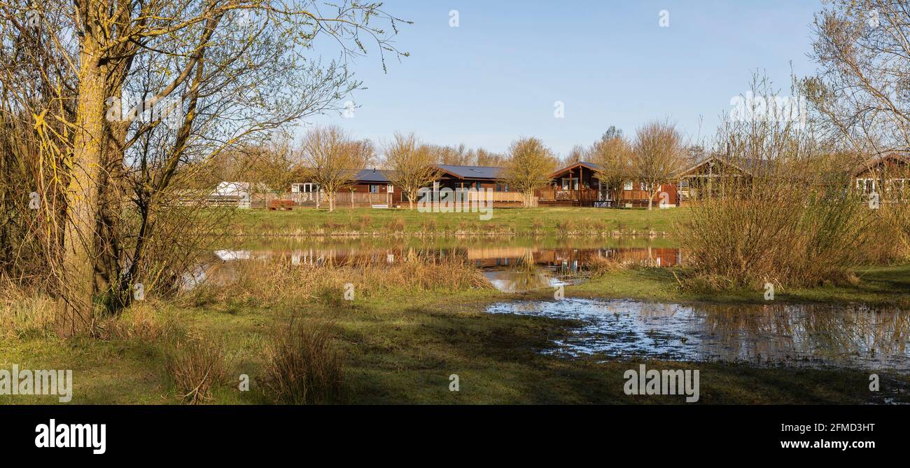 Una imagen de hermosas casas de madera rodadas a través del agua en Frisby Lakes, Leicestershire, Inglaterra, Reino Unido. Foto de stock