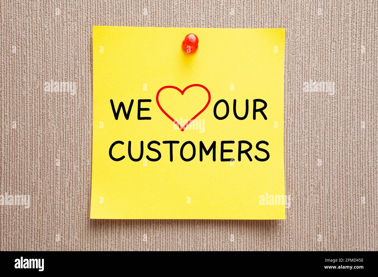 Texto Nos encanta a nuestros clientes escrito a mano en amarillo nota adhesiva. Concepto de satisfacción del cliente. Foto de stock