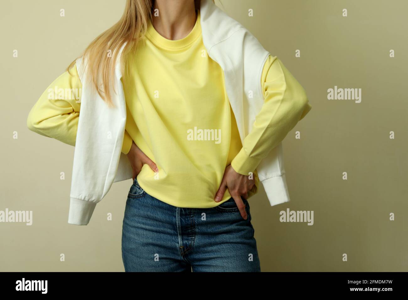 Mujer joven con sudadera amarilla sobre fondo beige Fotografía de stock -  Alamy