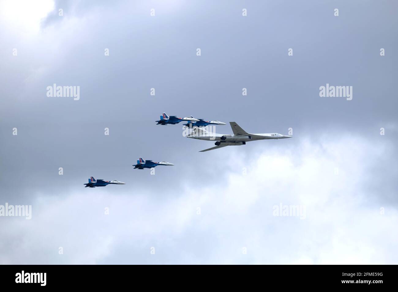 MOSCÚ, RUSIA - 7 de mayo de 2021: Ejército ruso Supersonic bombardero-misil portador TU-160 White Swan y cuatro combatientes SU-35S siguiendo por los lados Foto de stock