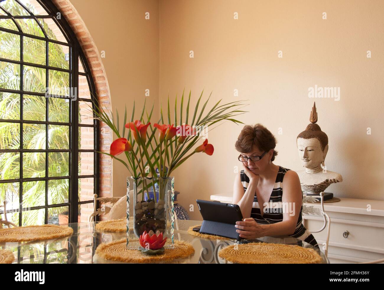 Mujer con la barbilla en mano estudia portátil en la mesa en elegante villa tropical - Puerto Vallarta, Jalisco, México. #613PV Foto de stock