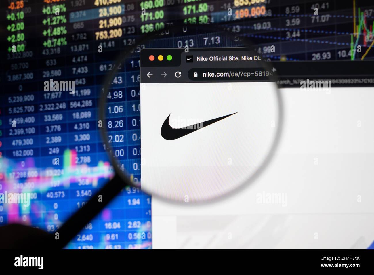 Logotipo de la empresa Nike en un sitio web con una evolución borrosa del  mercado de valores en segundo plano, visto en una pantalla de ordenador a  través de una lupa Fotografía