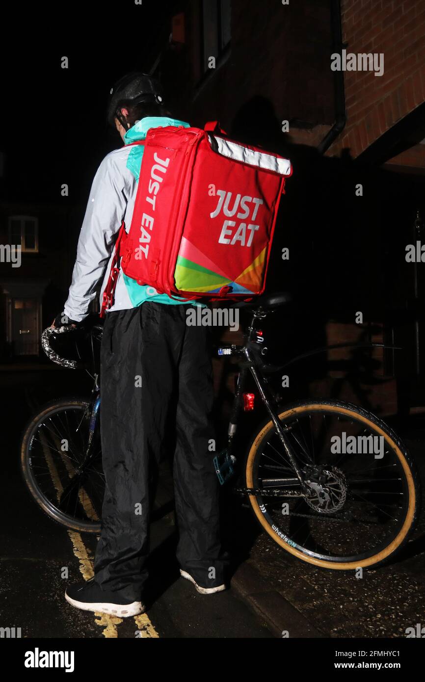 Un hombre de reparto de comida justa en su bicicleta en las calles oscuras  de Chichester, West Sussex, Reino Unido Fotografía de stock - Alamy