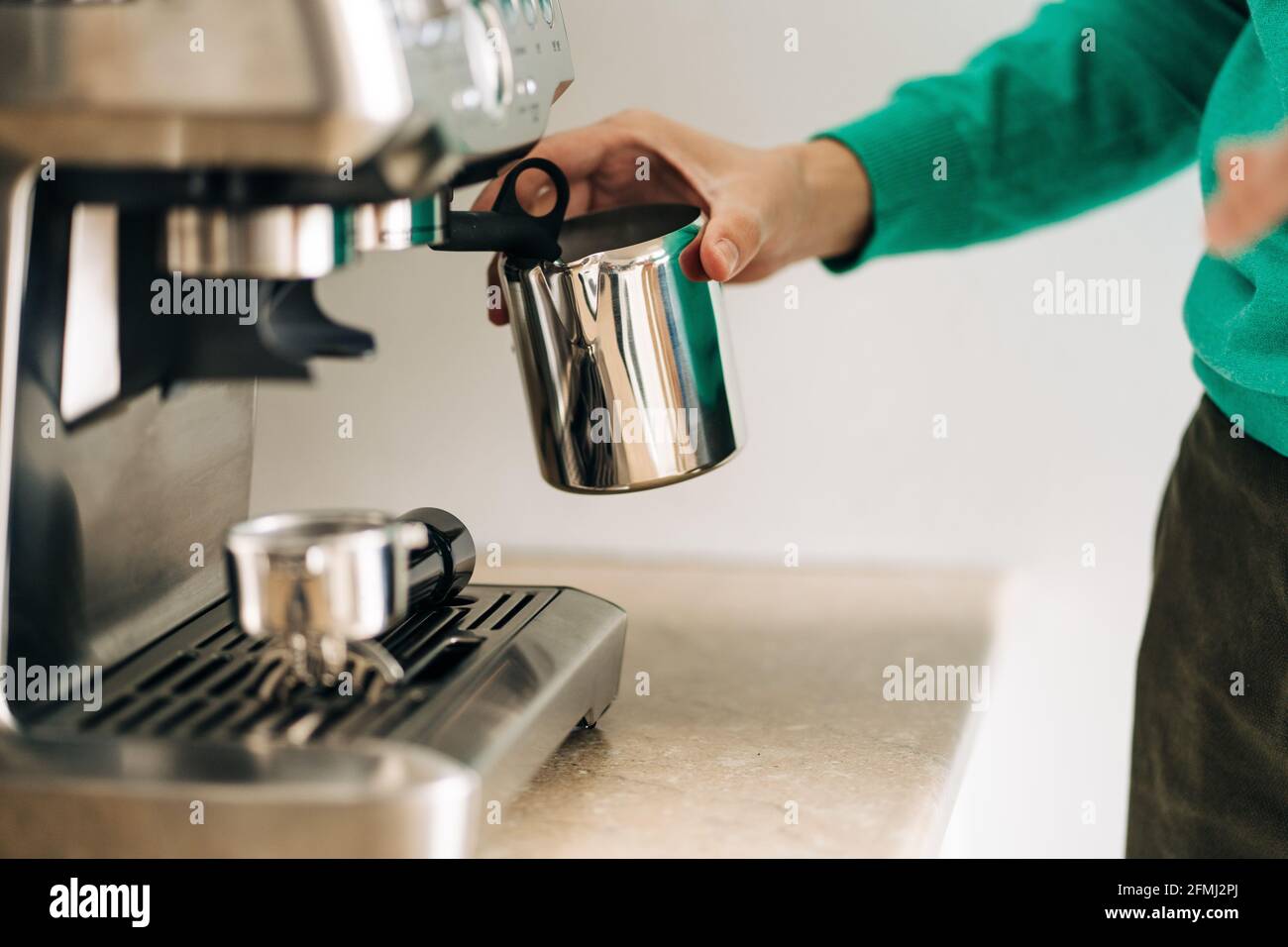 Corta a una persona irreconocible con una jarra metálica para preparar café  con un profesional máquina en la mesa de la casa Fotografía de stock - Alamy