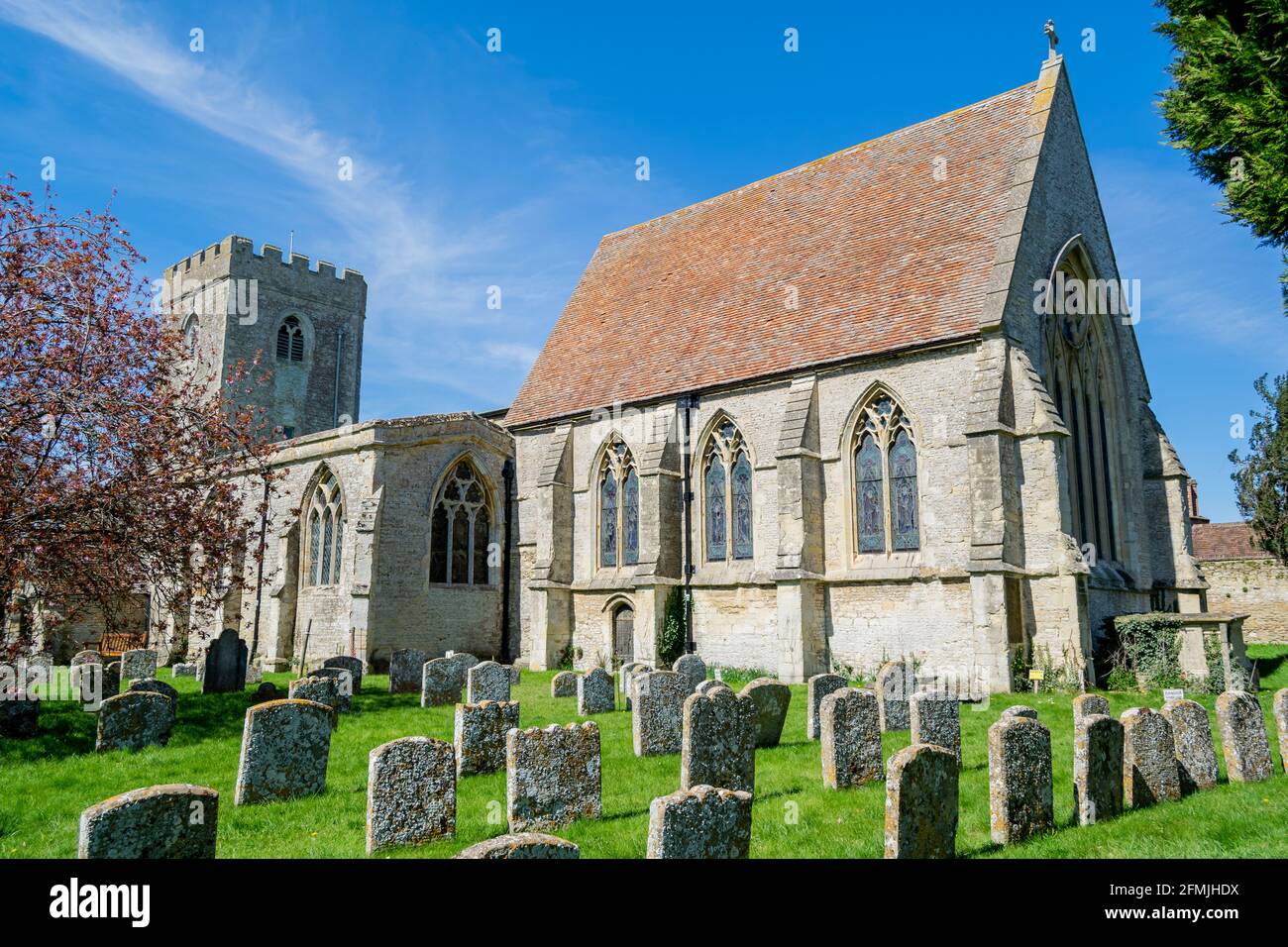 Great Haseley, UK-29 ?Apr?2021: Antigua iglesia inglesa de San Pedro y cementerio en primavera con hierba verde, flores bloomig alrededor y cielo azul de sol Foto de stock