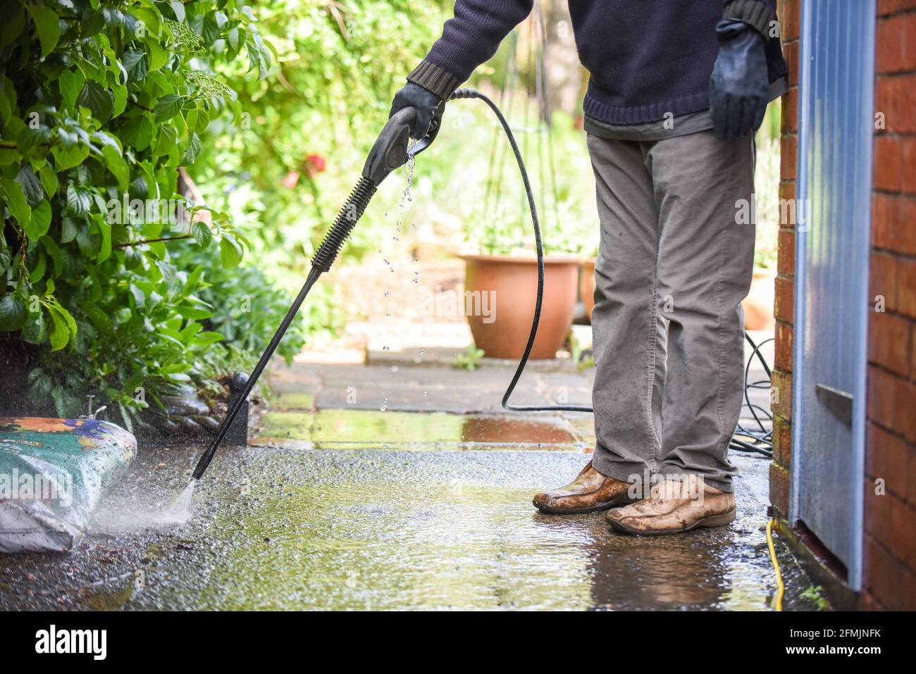 Limpieza de pavimentación de patio con una lavadora de alta presión el  hombre está utilizando el agua para limpiar el camino del jardín Fotografía  de stock - Alamy