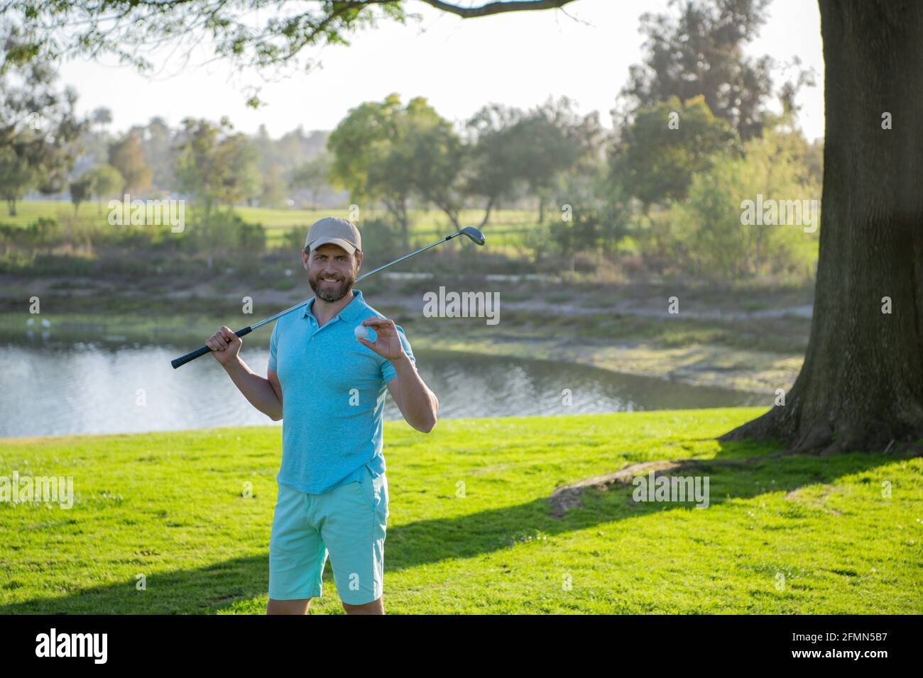 Retrato del golfista feliz del smilin que golpea tiro del golf con el club en el campo. Foto de stock