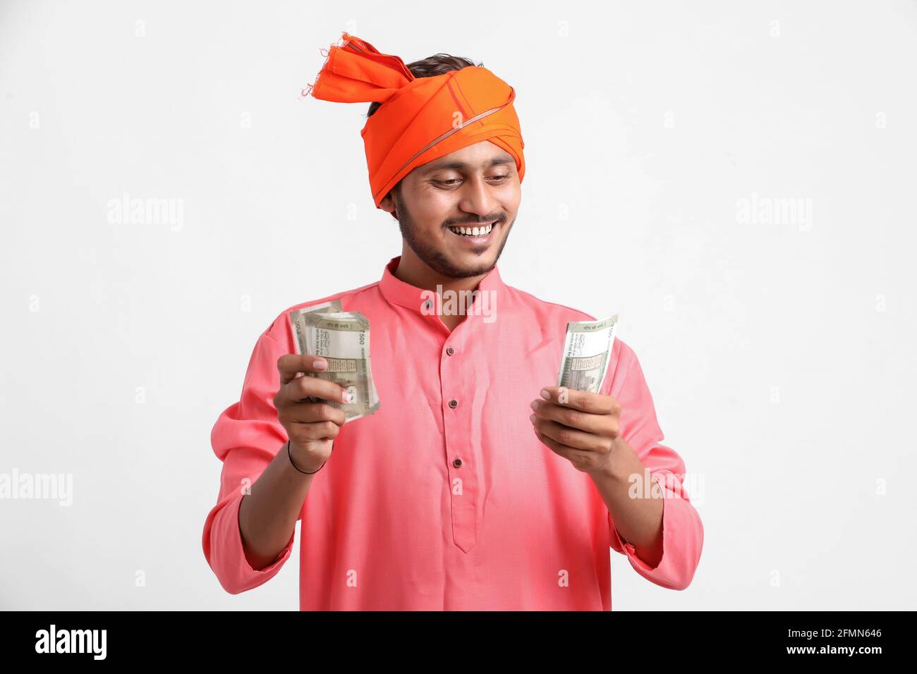 Joven agricultor indio posando con moneda sobre fondo blanco. Foto de stock