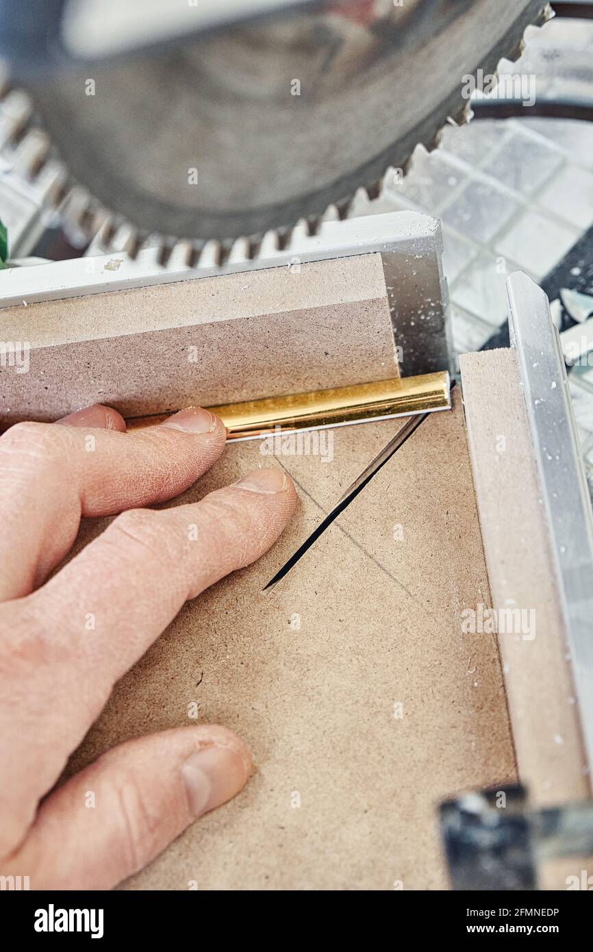 Tira decorativa de moldeado dorado para paneles de fachada de muebles en la sierra de inglete durante el proceso de fabricación Foto de stock