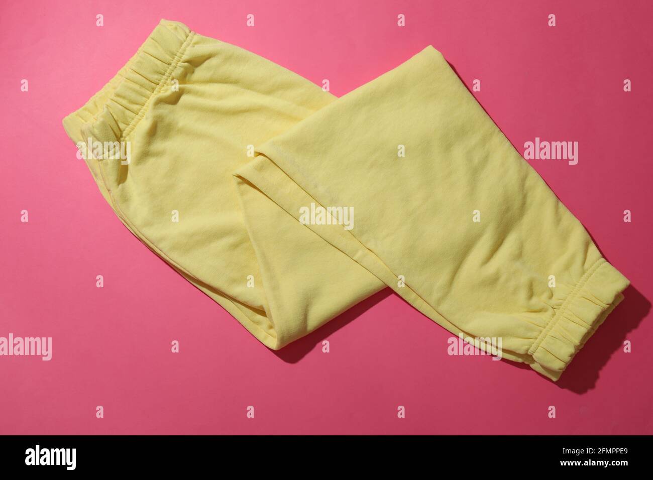Pantalones de chándal amarillos doblados sobre fondo rosa, vista superior  Fotografía de stock - Alamy