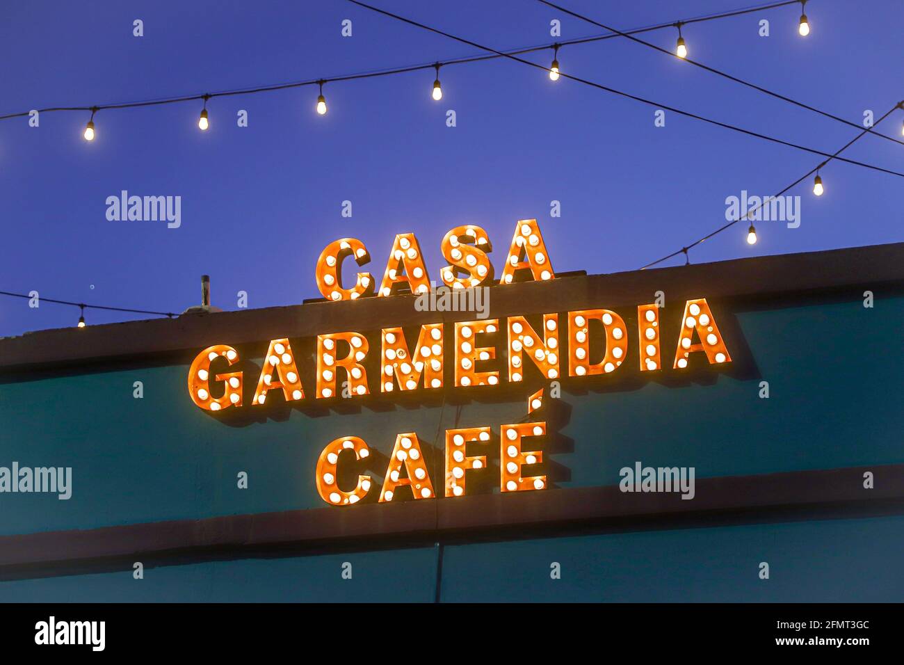 Signo LED, luz de neón con la leyenda Casa Garmendia Cafe. Escritura  central brillante y vívida y logotipo de neón LED naranja en el techo del  edificio contra el cielo azul y