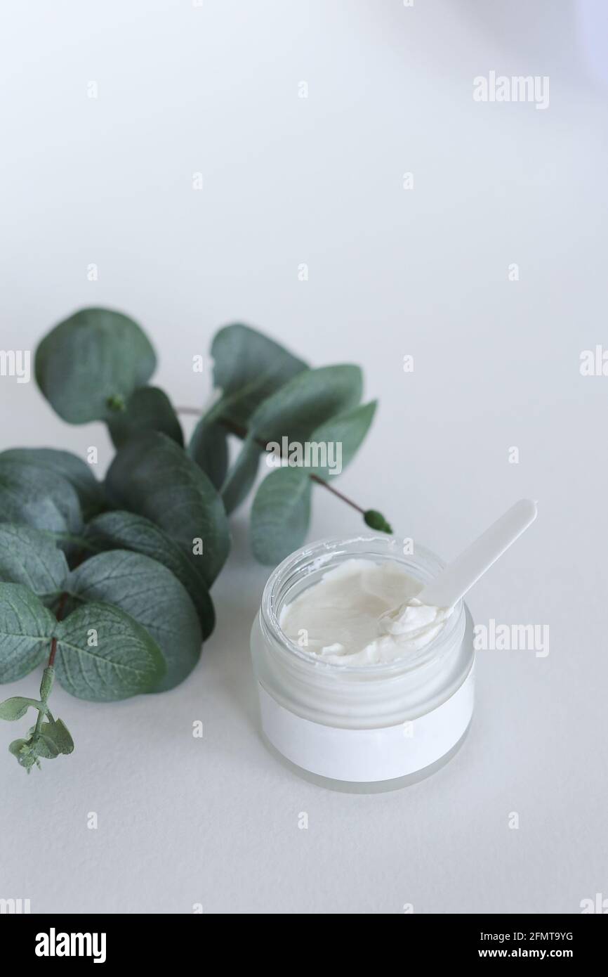 Crema cosmética hidratante con eucalipto se apoya sobre fondo neutro salpicaduras de leche Fotografía de stock - Alamy