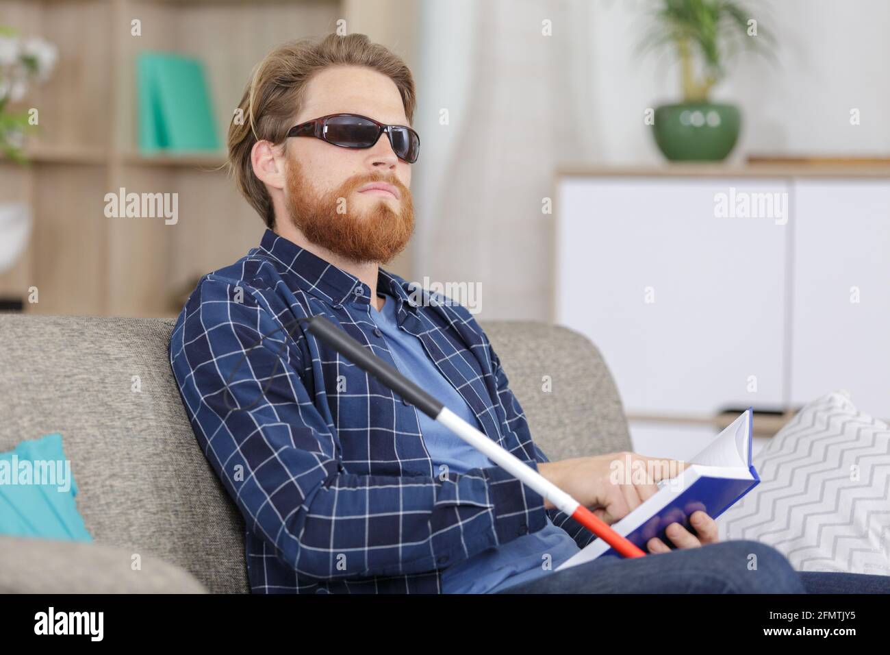 hombre ciego leyendo libro en el sofá Foto de stock