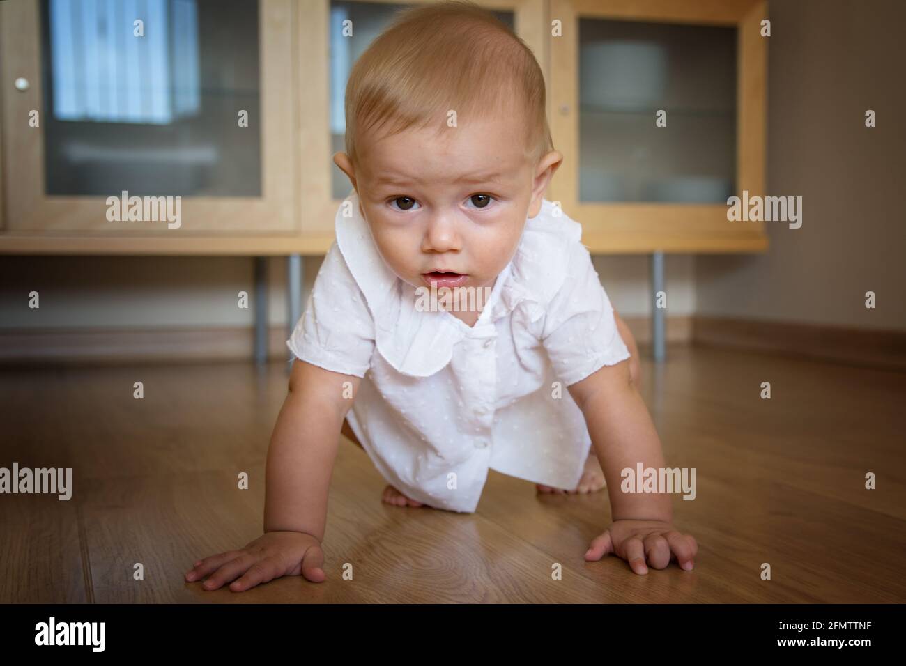 Hermoso bebé de 1-2 años arrastrándose en la sala de estar en casa. Foto de stock
