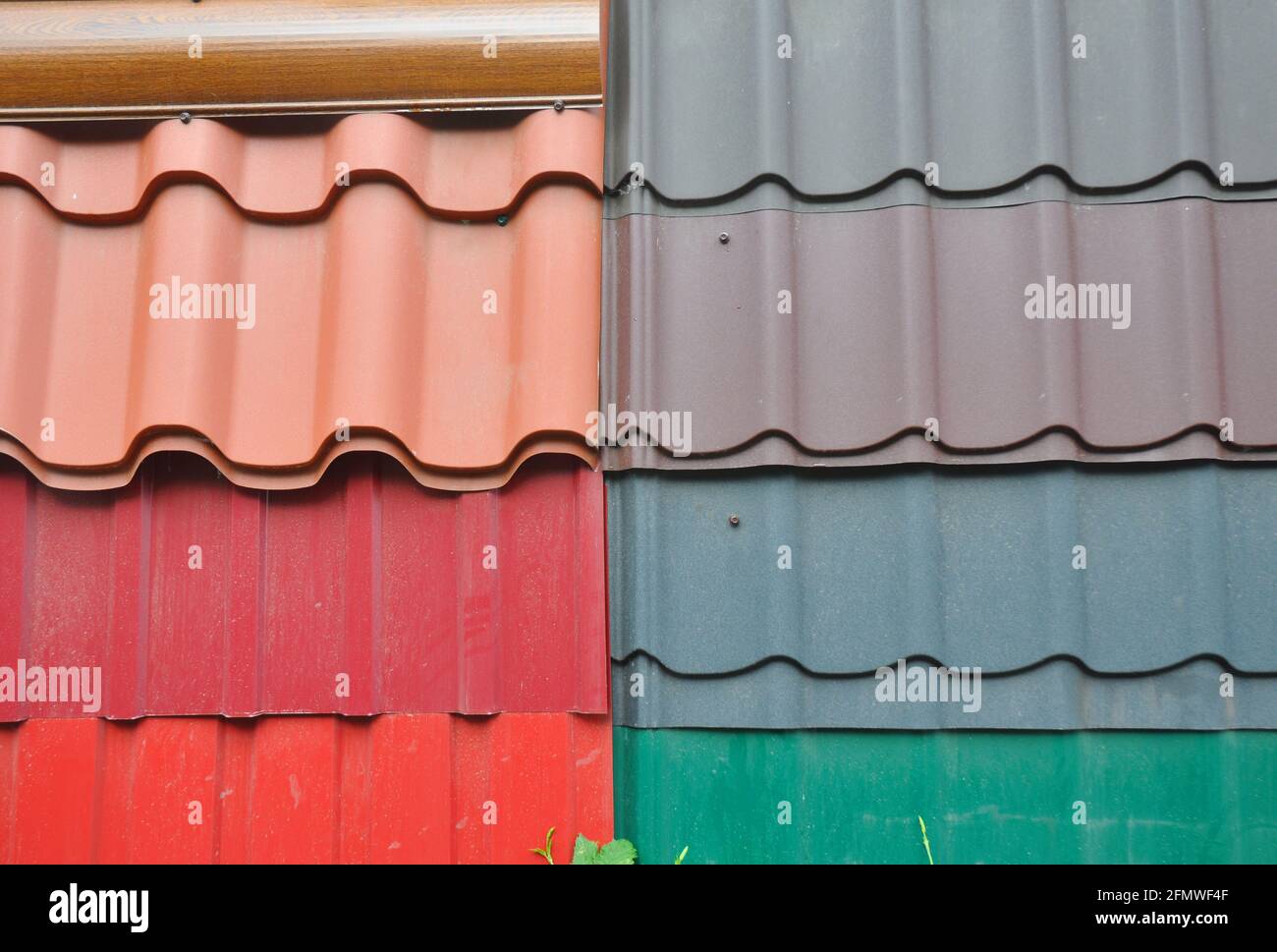 Una muestra de tejas metálicas de color naranja, rojo, gris, marrón y verde, diferentes tipos de tejas de metal corrugado para cubrir el techo de la casa. Foto de stock