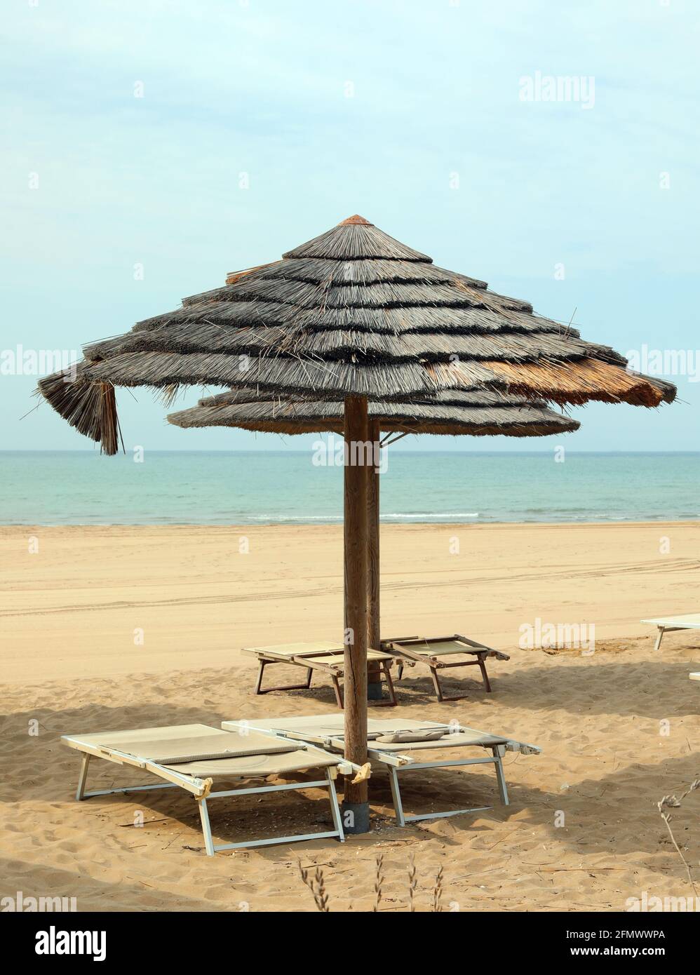 gran sombrilla de bambú en la orilla del mar sin gente y. hamacas vacías  Fotografía de stock - Alamy