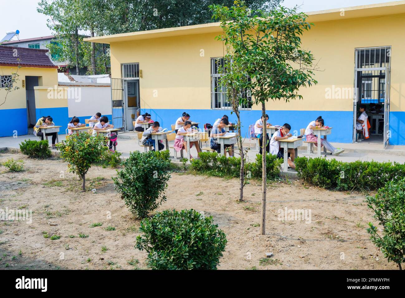 Estudiantes de primaria en una escuela rural en Qufu, Shandong, China, distanciándose social durante su clase. Foto de stock