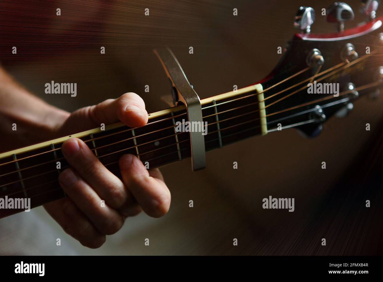 La mano de un hombre en el tablero de una guitarra corre sus dedos a través  de las cuerdas y sujeta los acordes. Música instrumental, lección de  guitarra sobre partituras Fotografía de