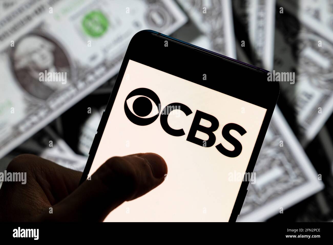 En esta ilustración de la foto, el logotipo de la cadena CBS de televisión  y radio comercial en inglés americano aparece en un smartphone con una  moneda de fondo en USD (dólares