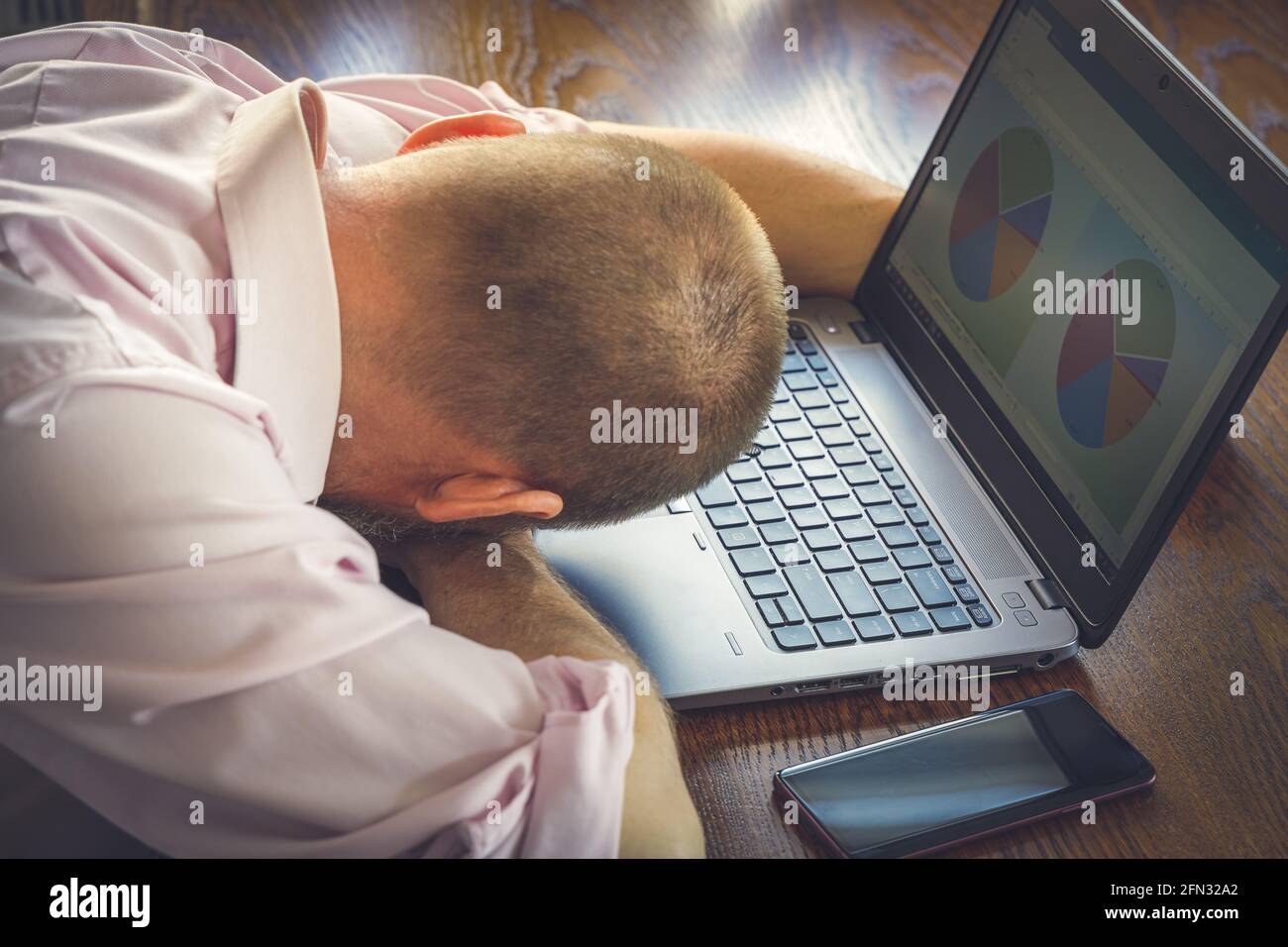 Trabajador de oficina cansado que se va de casa, teniendo la siesta junto al ordenador portátil Foto de stock