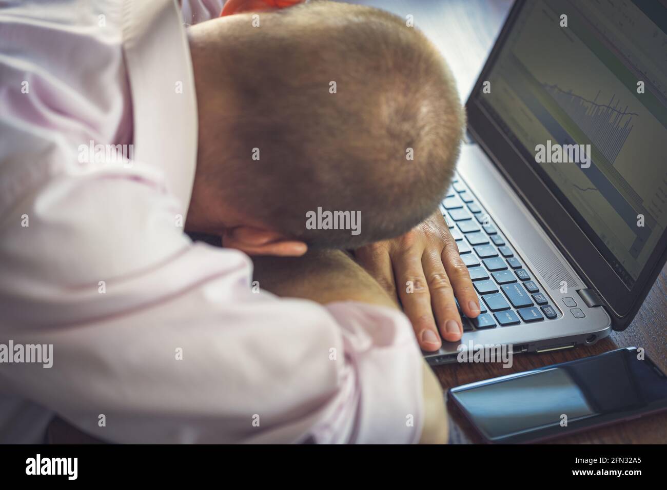 Trabajador de oficina cansado que se va de casa, teniendo la siesta junto al ordenador portátil Foto de stock