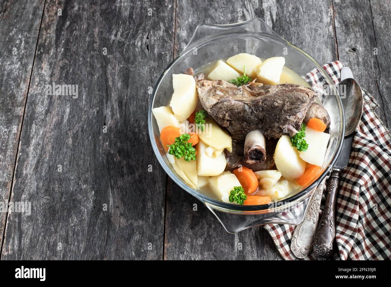 Guiso de media pierna de cordero con verduras en una olla de cristal mesa  de madera Fotografía de stock - Alamy