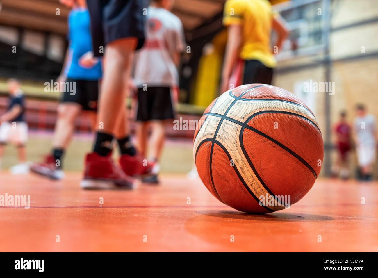 Pelota de baloncesto en el suelo en el gimnasio deportivo en el enfoque selectivo en la corte con borrosos de niños desconocidos concepto de deporte de entrenamiento y desarrollo Fotografía de