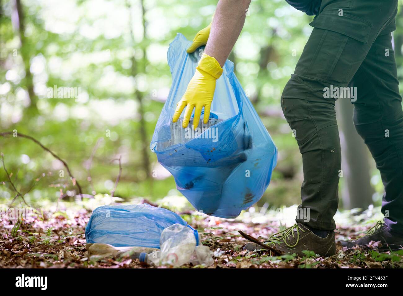 Mano recogiendo plástico de basura para limpiar los bosques o parques