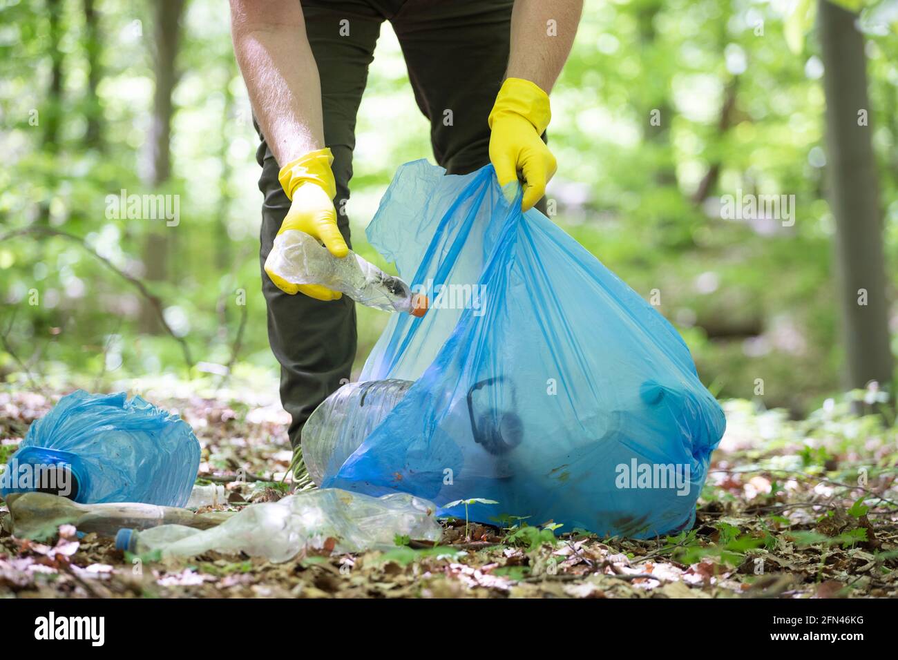 Mano recogiendo plástico de basura para limpiar los bosques o parques.  Protección ambiental, Día de la Tierra, concepto de voluntariado Fotografía  de stock - Alamy