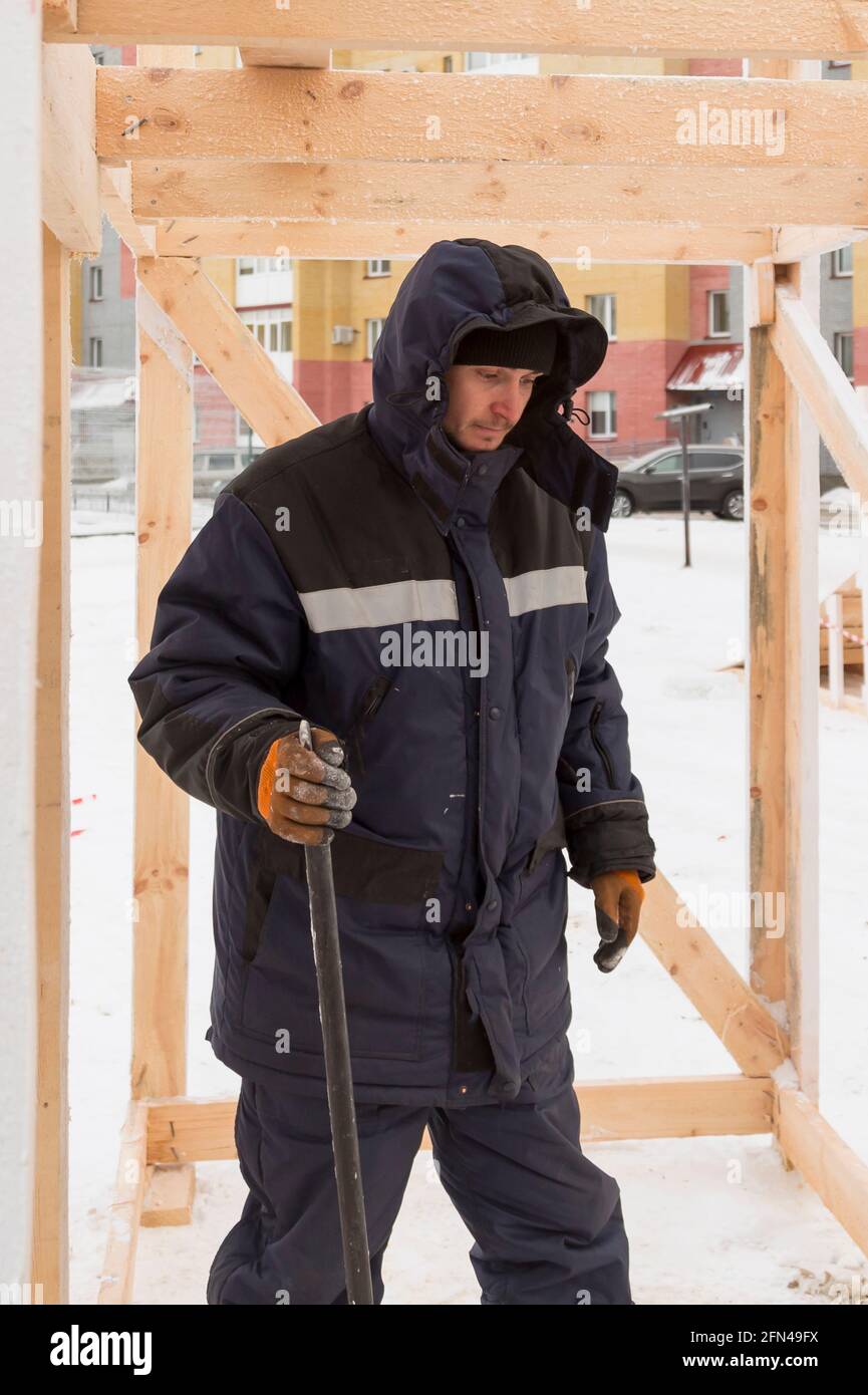 Trabajador en la construcción del marco de madera con crowbar en la mano Foto de stock