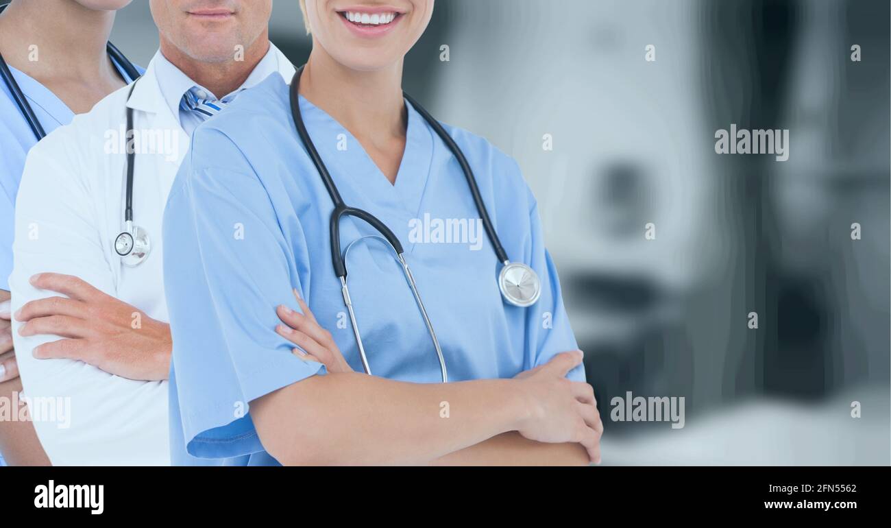 Sección media del equipo de profesionales médicos y trabajadores de la salud contra el hospital en segundo plano Foto de stock
