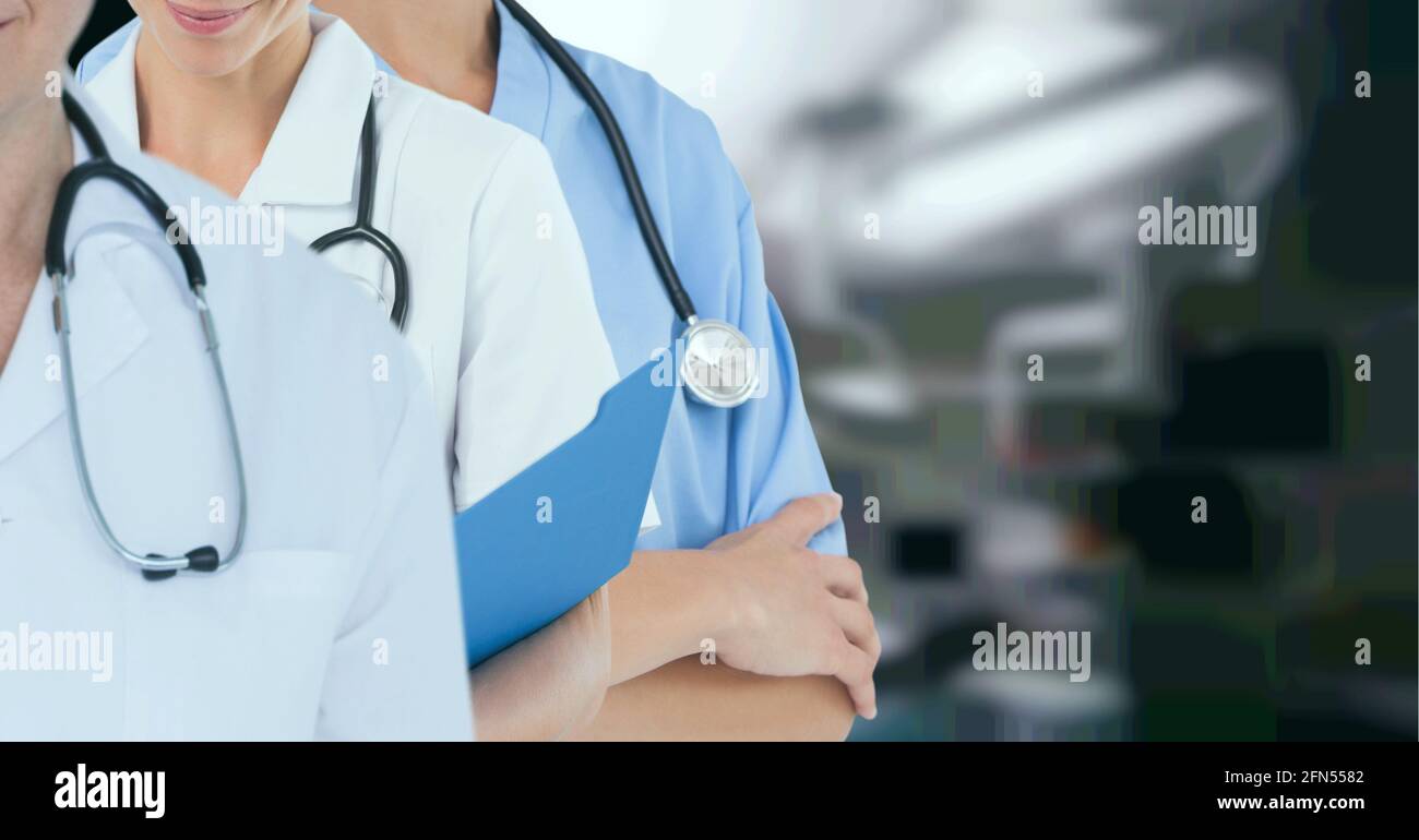 Sección media del equipo de profesionales médicos y trabajadores de la salud contra el hospital en segundo plano Foto de stock