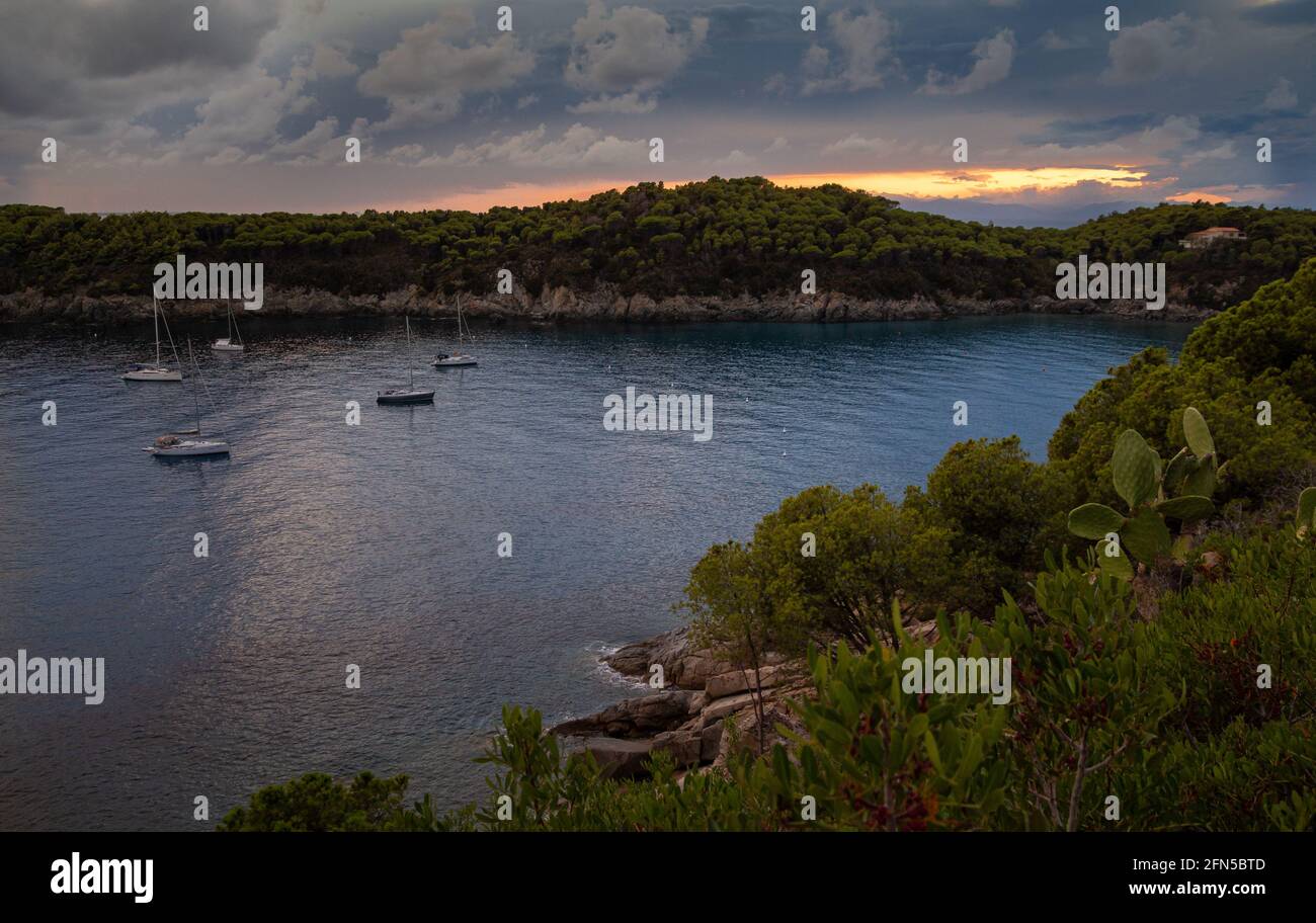 Vista panorámica de los veleros sobre el agua en la espectacular vista puesta de sol en la playa vacía de Fetovaia, Isla de Elba, Toscana, Italia Foto de stock