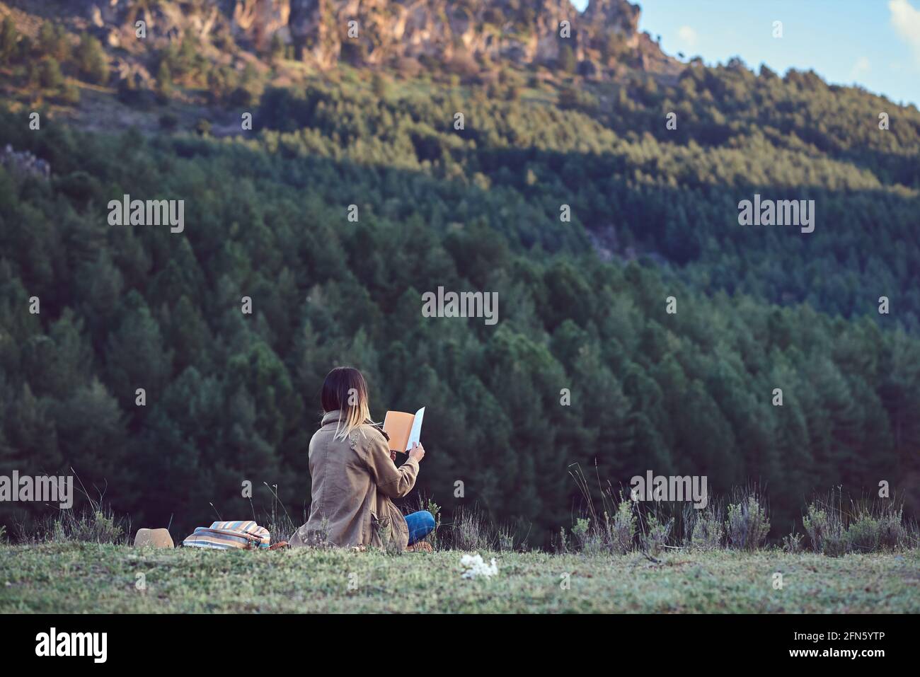 Mujer en la montaña leyendo un libro Foto de stock
