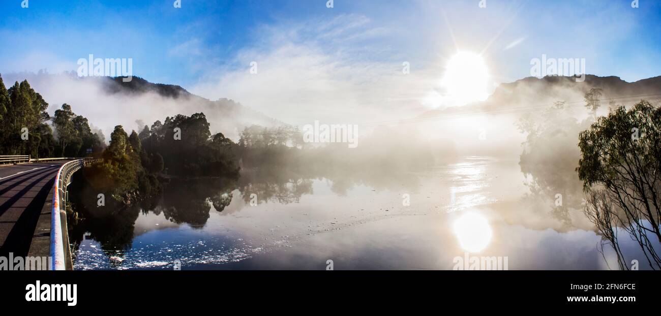 Paisaje panorámico panorámico de neblina a primera hora de la mañana en el lago Rosebery, en Tullah Tasmania, Australia, con el sol reventando sobre los picos de la montaña y la ref Foto de stock
