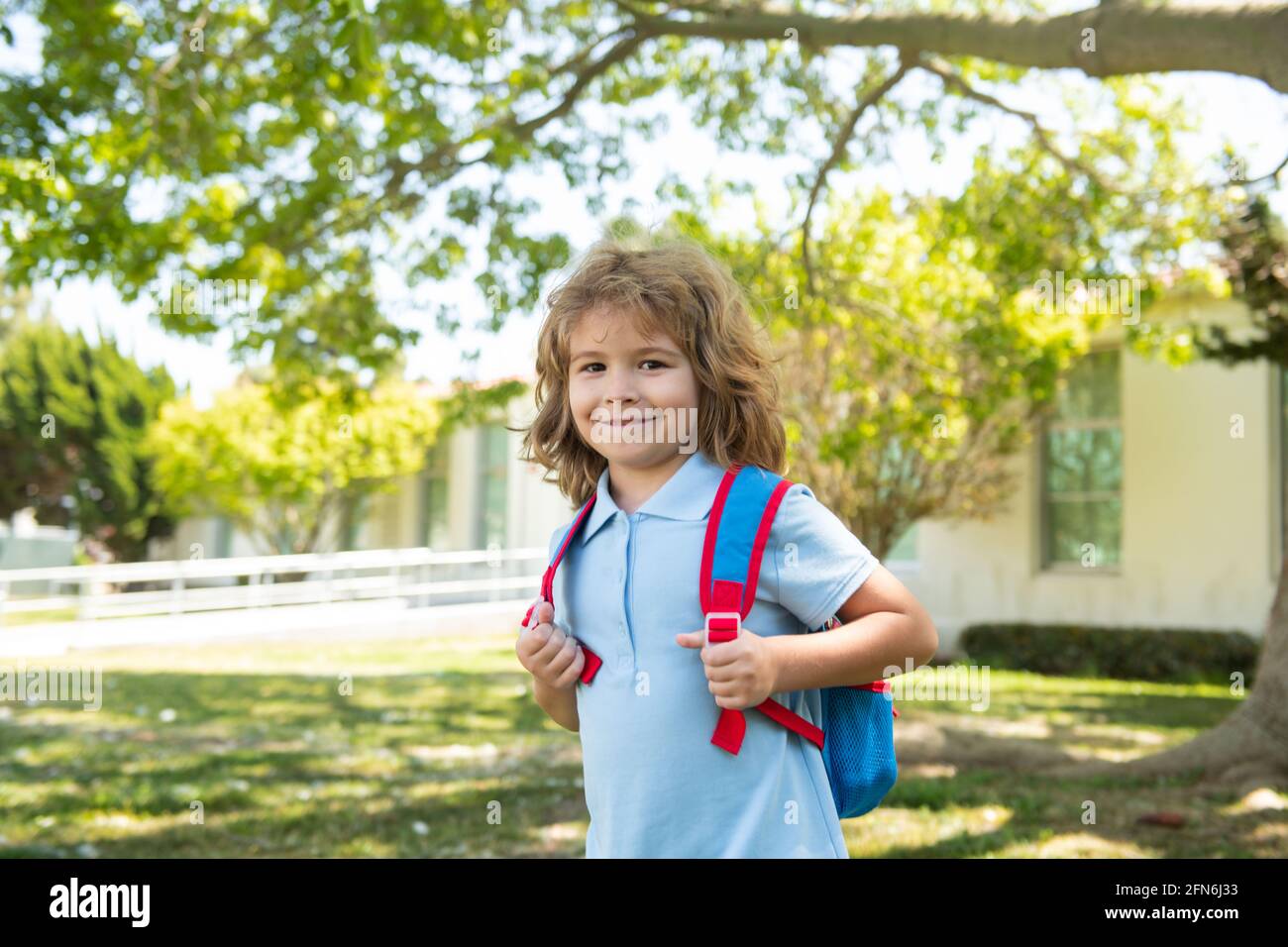Niño con mochila yendo la escuela. Concepto de educación infantil. Niño con de pie en el parque cerca de la escuela. Alumnos con libros y mochilas Fotografía de stock -