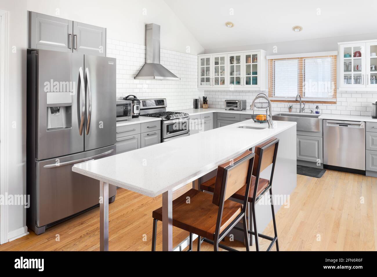 Una hermosa cocina renovada con armarios grises y blancos, electrodomésticos  de acero inoxidable, una gran isla blanca, y salpicadero de azulejos del  metro Fotografía de stock - Alamy