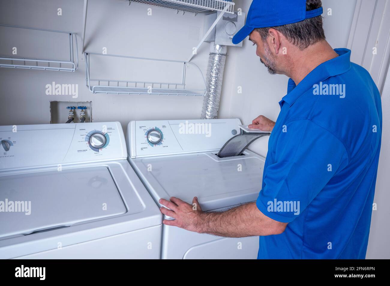 Técnico profesional de electrodomésticos que comprueba una trampa de pelusas en una zona residencial secador Foto de stock