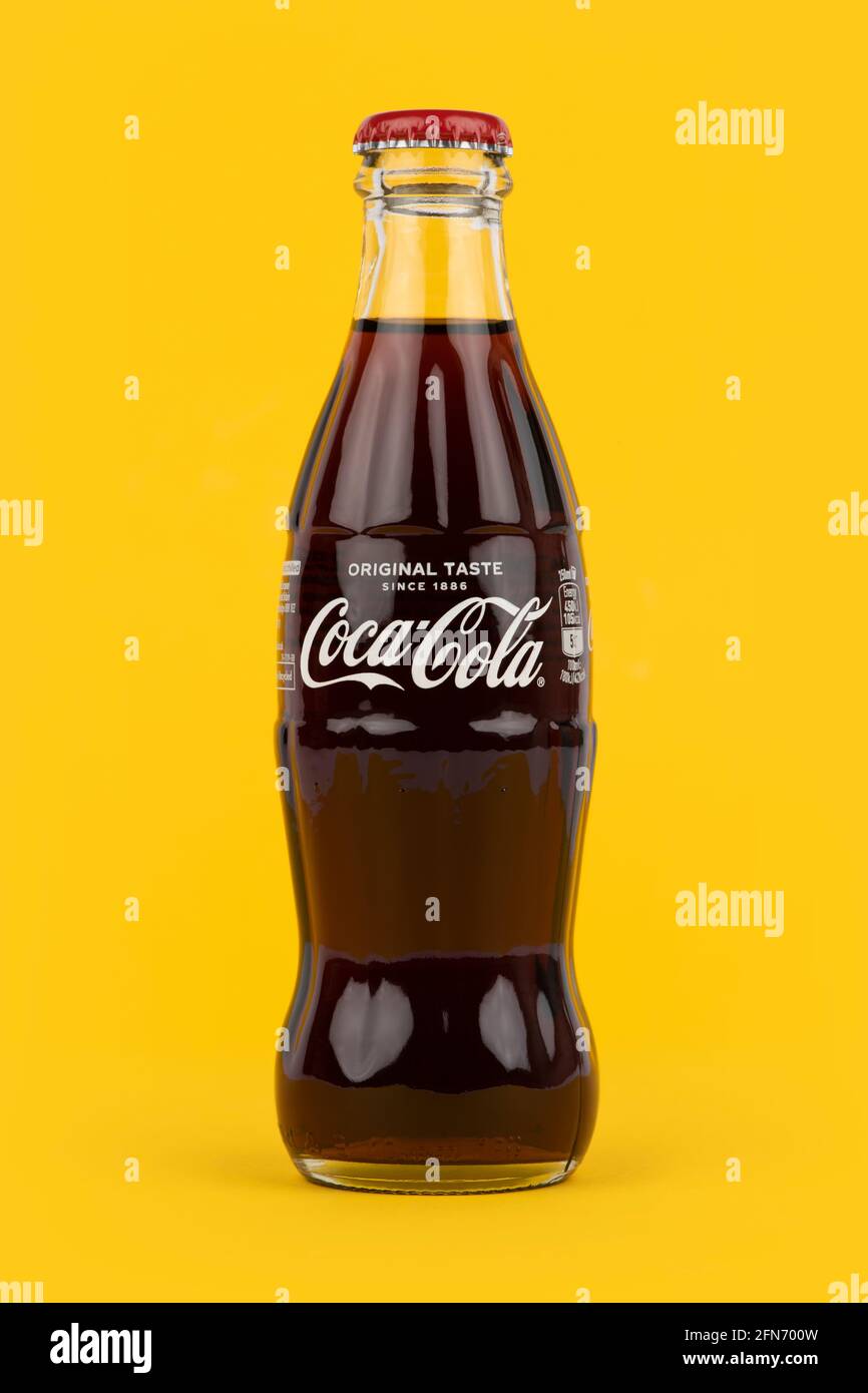Una botella de Coca-Cola de forma tradicional rodada sobre un fondo amarillo. Foto de stock
