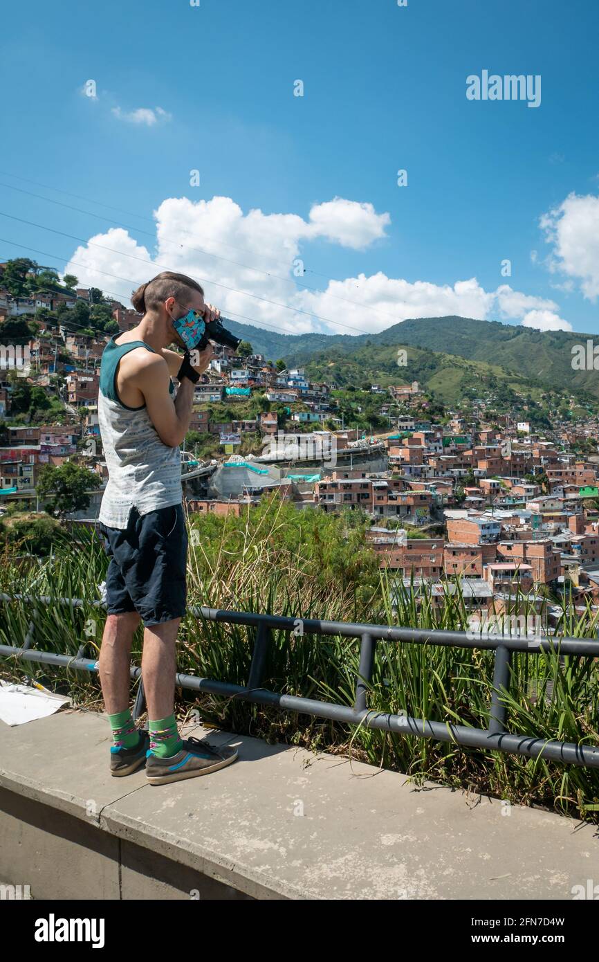 Medellín, Antioquia, Colombia - Diciembre 23 2020: Un joven caucásico está tomando una foto con una cámara negra en la Comuna 13, un Barrio Turístico Foto de stock
