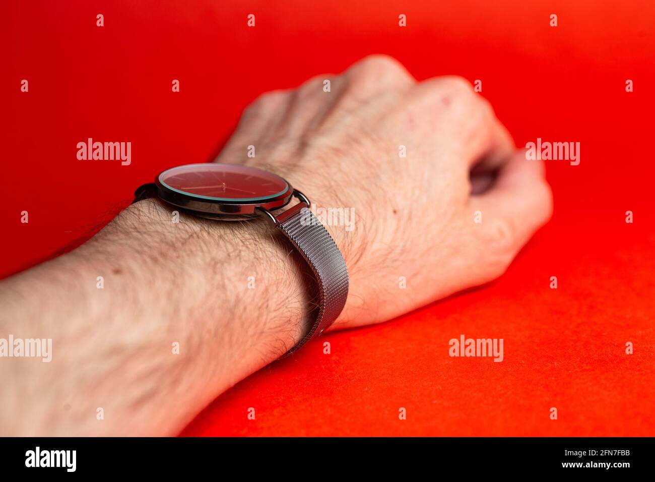 reloj de pulsera en la mano de un hombre sobre un fondo rojo Fotografía de  stock - Alamy