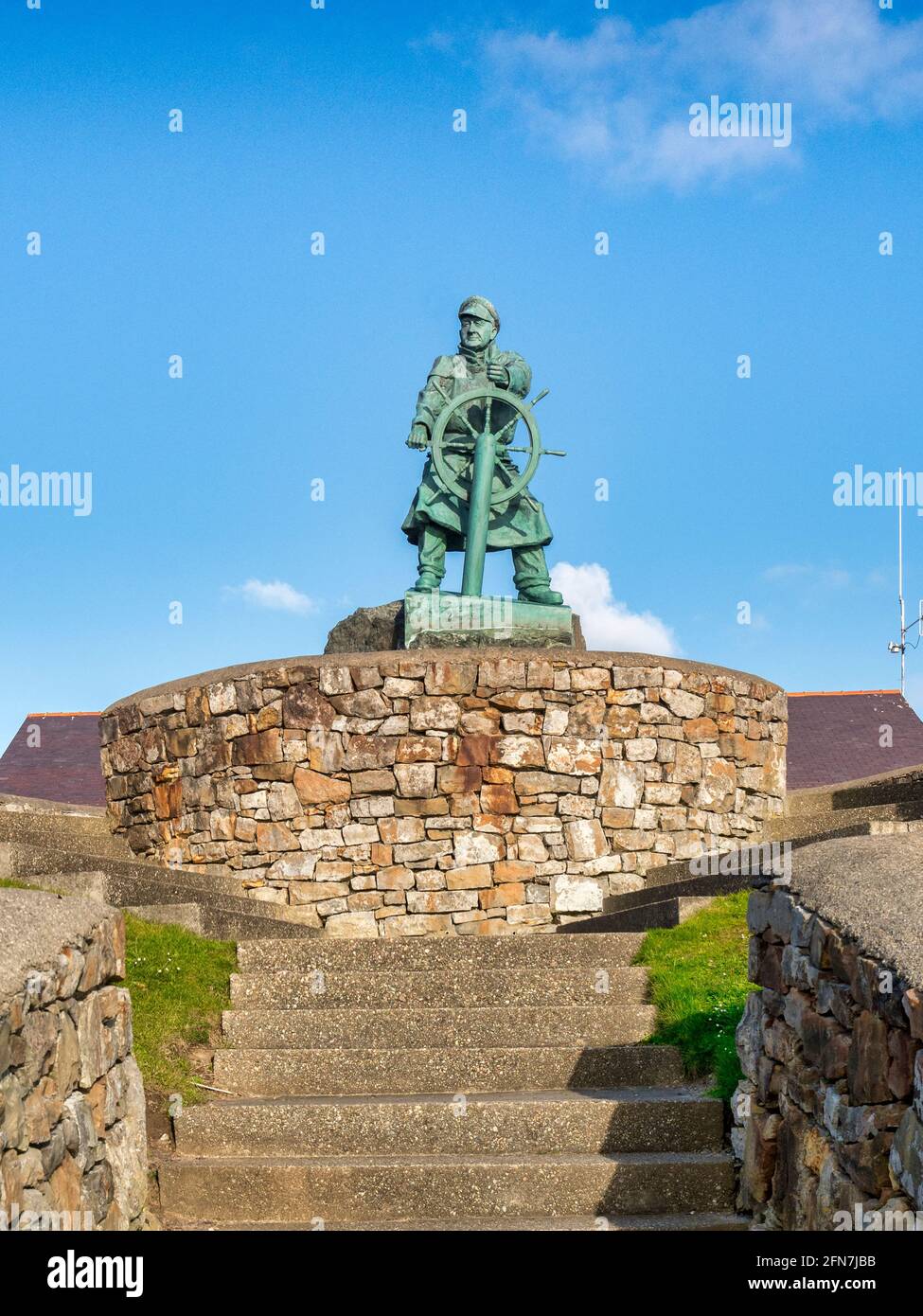 Escultura de Richard 'Dic' Evans, un coxswain altamente decorado del barco salvavidas local, frente al Centro de Visitantes RNLI en Moelfre, en la costa este Foto de stock