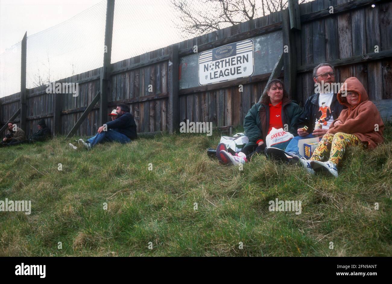 Una familia sentada teniendo un picnic mientras observaba un partido de fútbol de no-liga Foto de stock