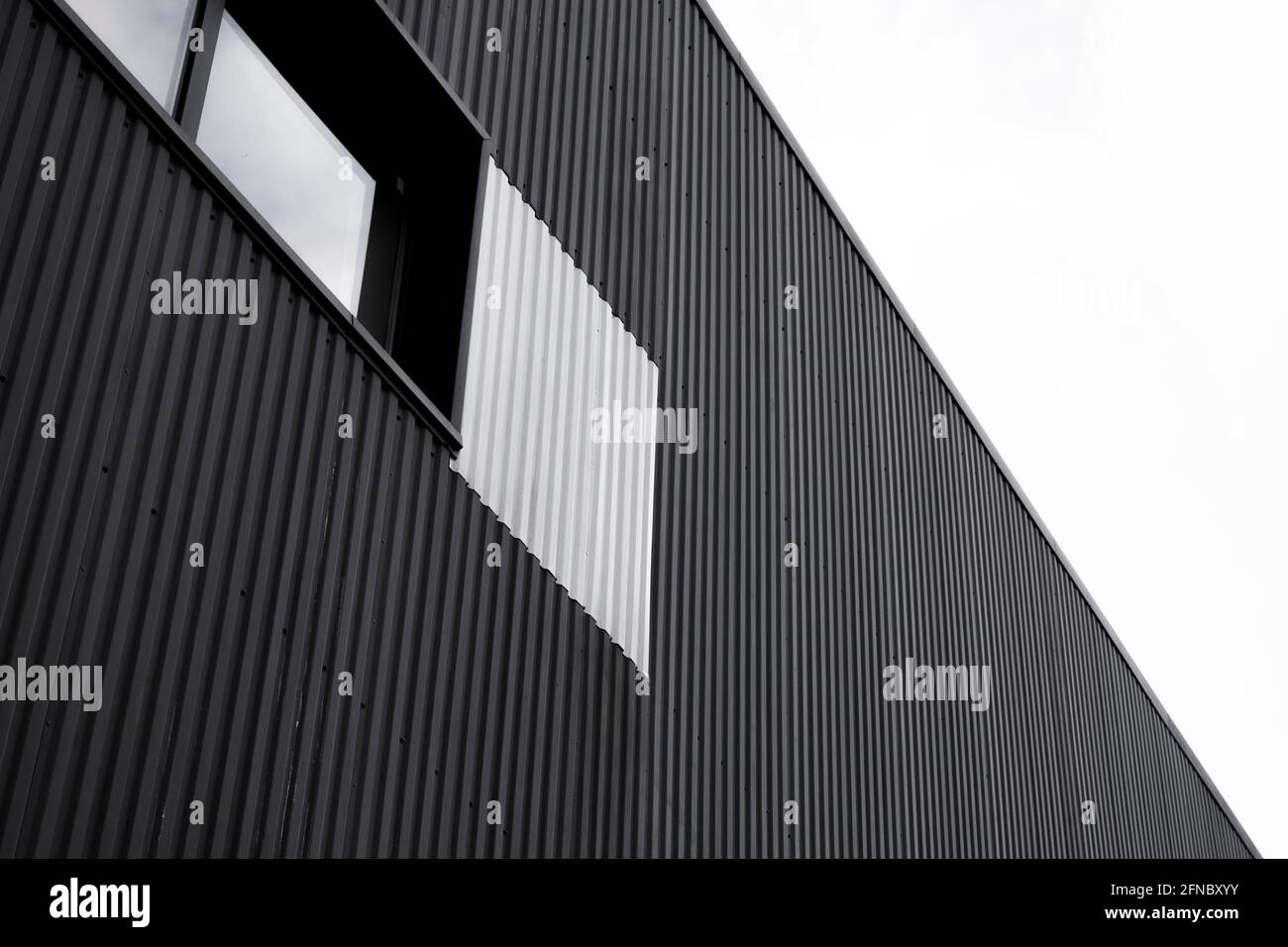 Chapa negra de hierro corrugado utilizada como fachada de un almacén o  fábrica. Textura de una fachada de aluminio de chapa metálica de zinc  corrugado sin costuras Fotografía de stock - Alamy