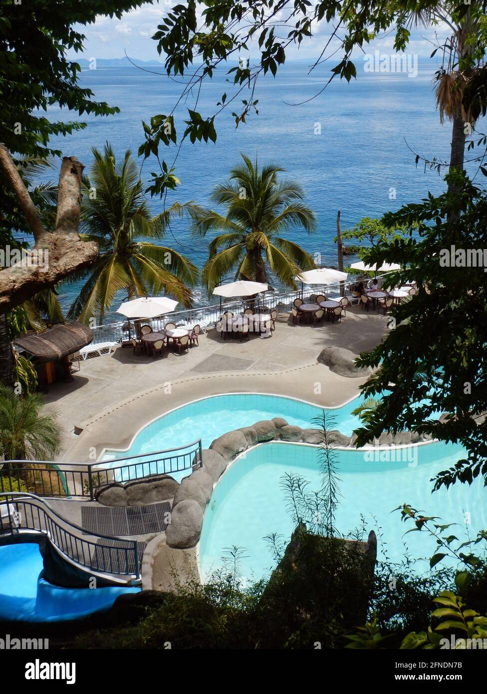 Preciosas vistas de las piscinas con mesas y sillas en un complejo que supervisa el océano Pacífico en Eagle Point, Batangas, Lozon, Filipinas Foto de stock