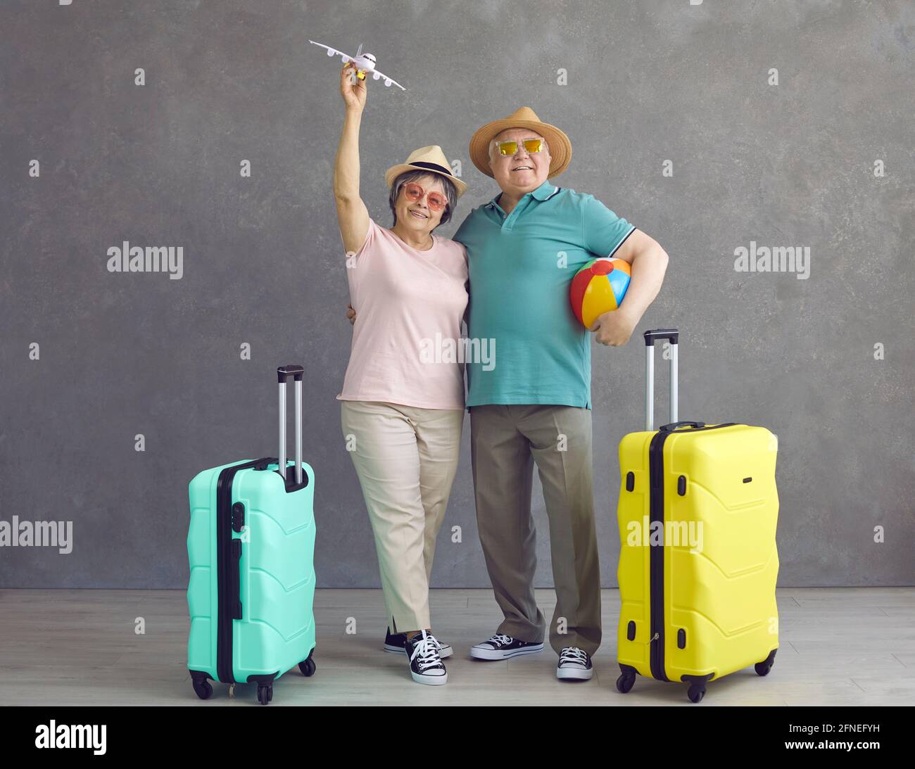 Estudio retrato de feliz pareja mayor en sombreros y gafas de sol con avión  de papel y maletas Fotografía de stock - Alamy