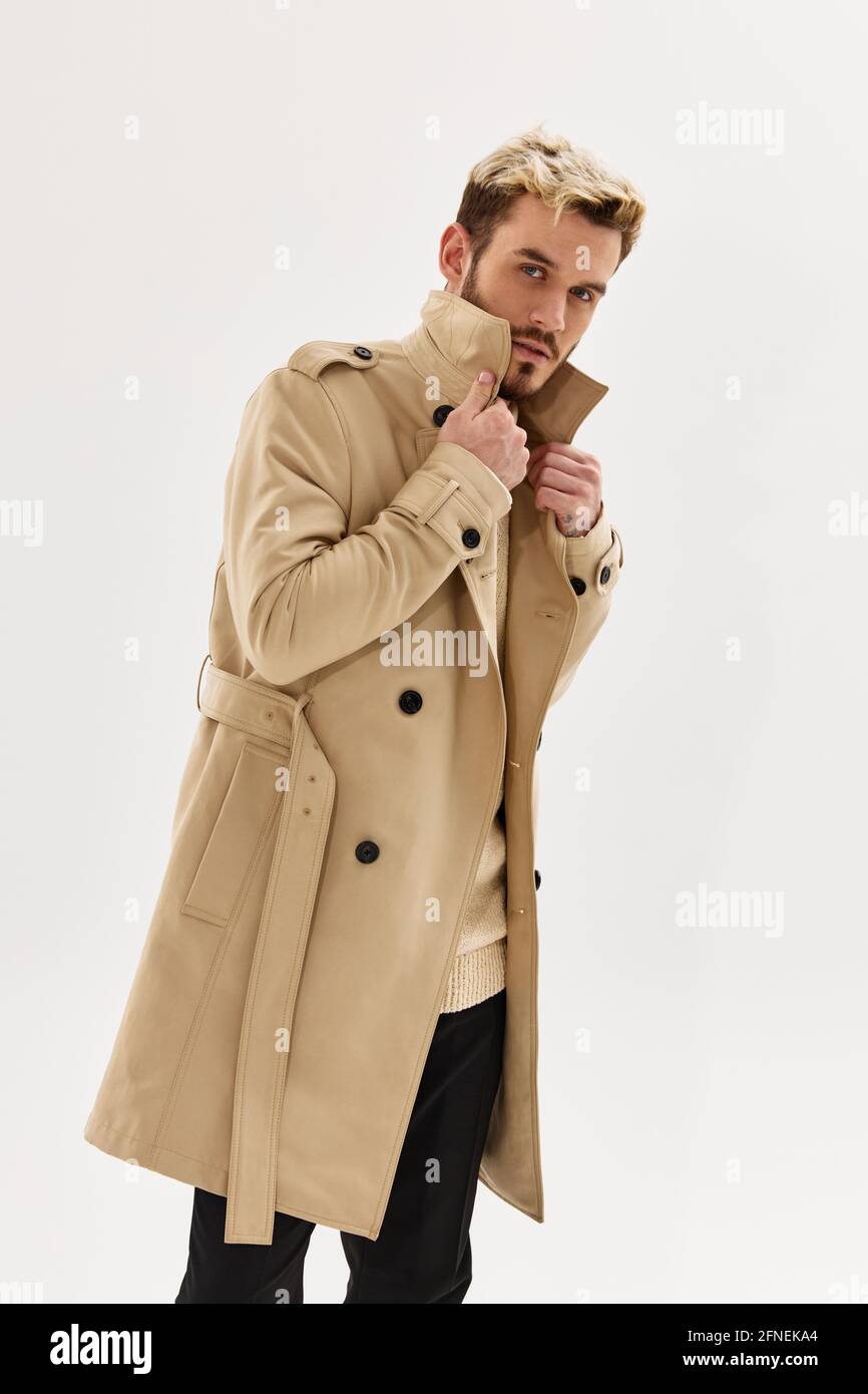 hombre en color beige abrigo moda atractivo aspecto de fondo claro  Fotografía de stock - Alamy