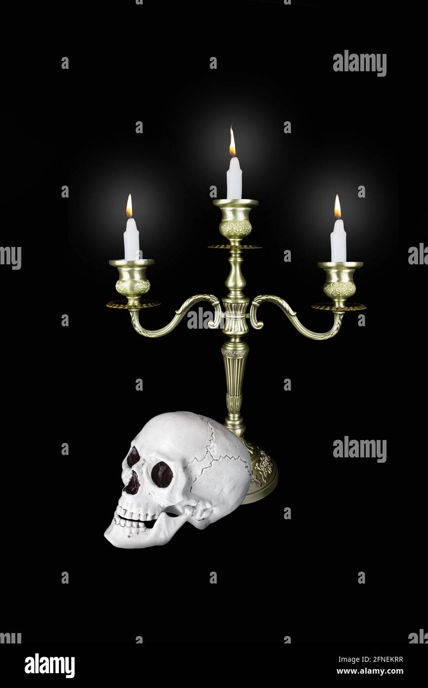 Candelabro triple de bronce con tres velas encendidas y cráneo humano sobre  fondo negro Fotografía de stock - Alamy